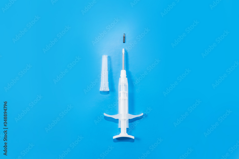 syringe with a microchip on a blue background, chipping, nobody, view from above
