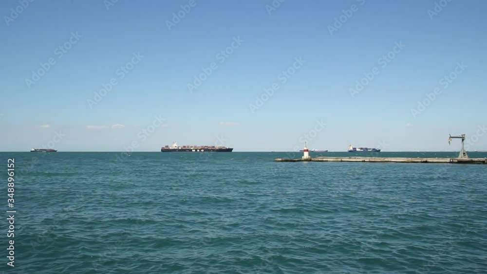 Pier in the sea, blue water, cargo ships in the background, idyllic blue sky, Thessaloniki Greece Pier in the sea, blue water, cargo ships in the background, idyllic blue sky, Thessaloniki Greece