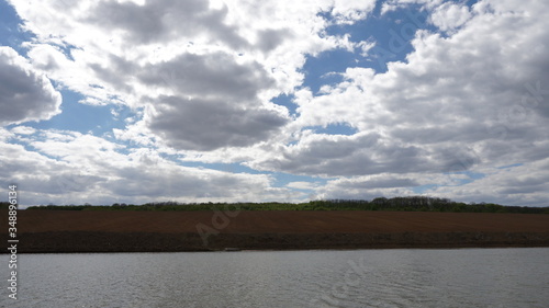 Forest and field near the river. Blue sky. View from below