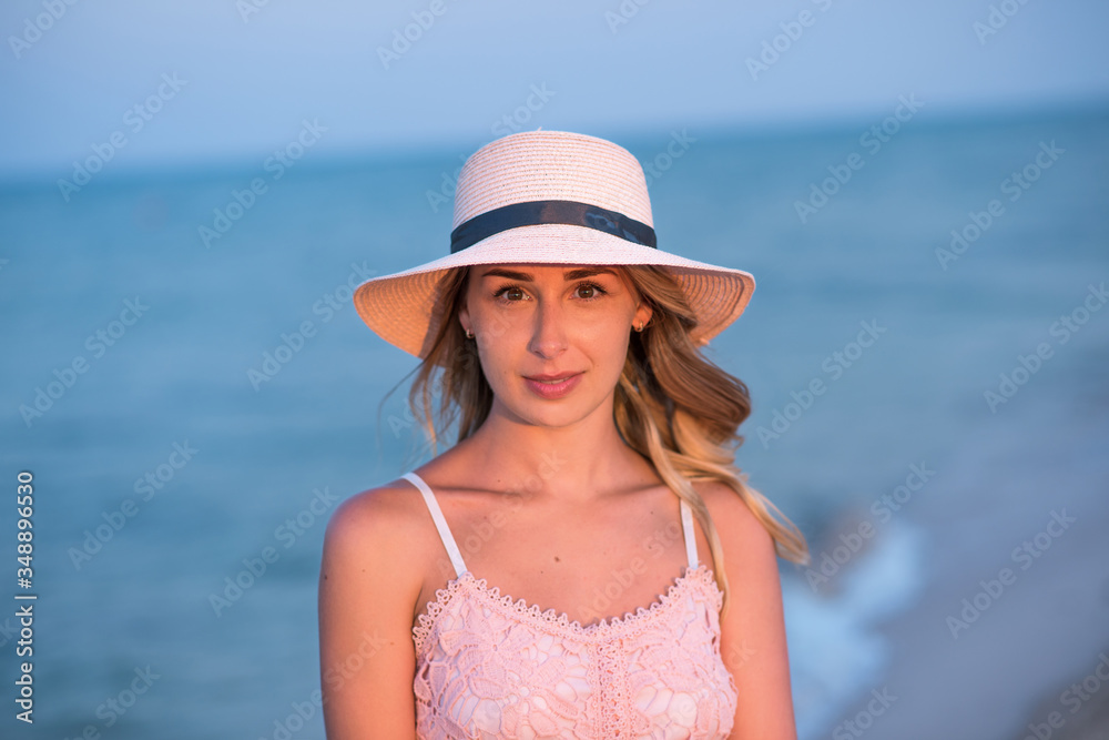 girl with a ball on the beach. young woman in hat on the beach. young woman in pink dress on the beach. 
Holidays at sea.