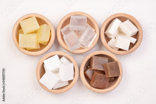 Five kinds of glycerin soap bases in wooden bowls on white wooden background photo