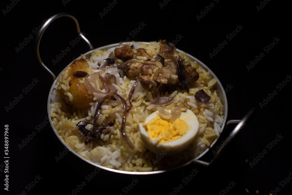 Indian spicy dish Biryani with egg, potato and Chicken in a pot in dark copy space background. Food and object photography. Indian spicy dish Biryani with egg, potato and Chicken in a pot in dark copy space background. Food and object photography.