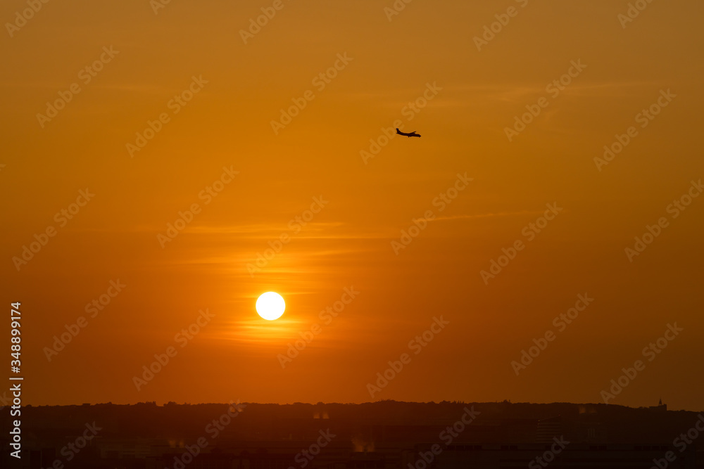 Seting sun with an airplane silhouette in colourful sky background