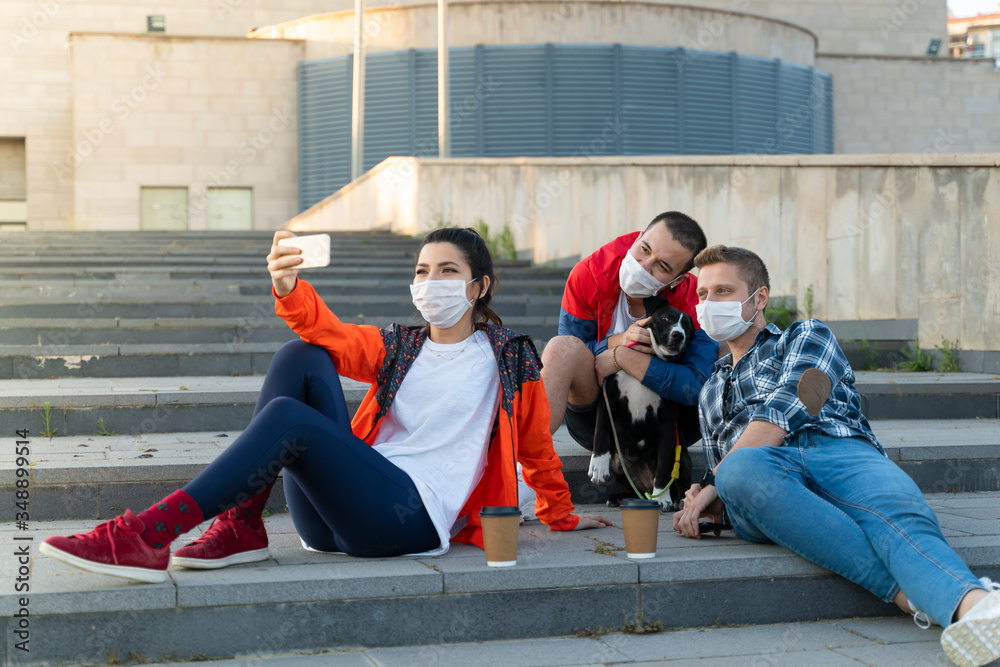 Cheerful university student taking selfie with friends sitting on steps Cheerful university student taking selfie with friends sitting on steps