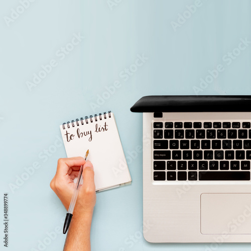 Businessman planning buying list and investments, with laptop and copy space. Flat lay