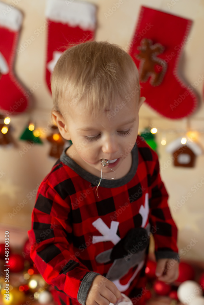 a little boy in Christmas pajamas with a toy in his mouth . new year. a child on Christmas morning a little boy in Christmas pajamas with a toy in his mouth . new year. a child on Christmas morning