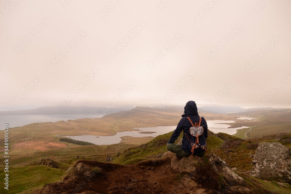 Fototapeta premium Young hiker woman sitting on the top of the hill in Scotland