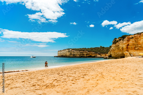 Young couple enjoying beautiful, sandy beach with cliffs in Algarve, Portugal © eunikas