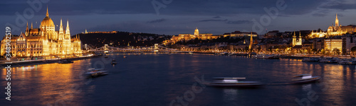 Budapest panorama at night with Parliament building and castle illuminated by city lights and reflection in the danube river.