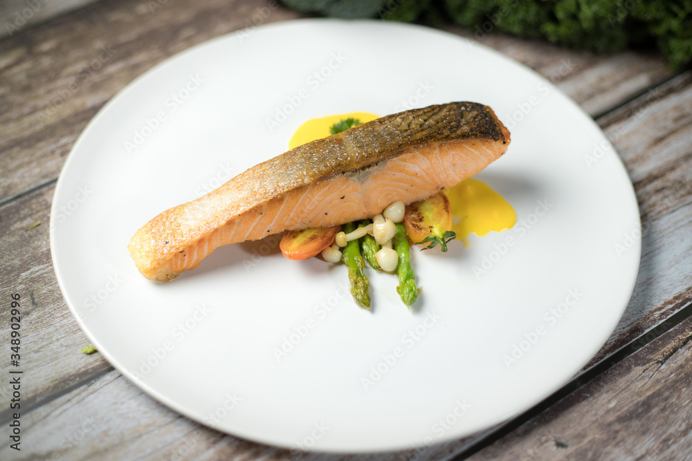 Salmon Steak.Grilled salmon with yellow cream sauce and asparagus on a white plate Salmon Steak.Grilled salmon with yellow cream sauce and asparagus on a white plate