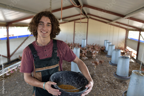 Smiling young farmer standing in henhouse photo