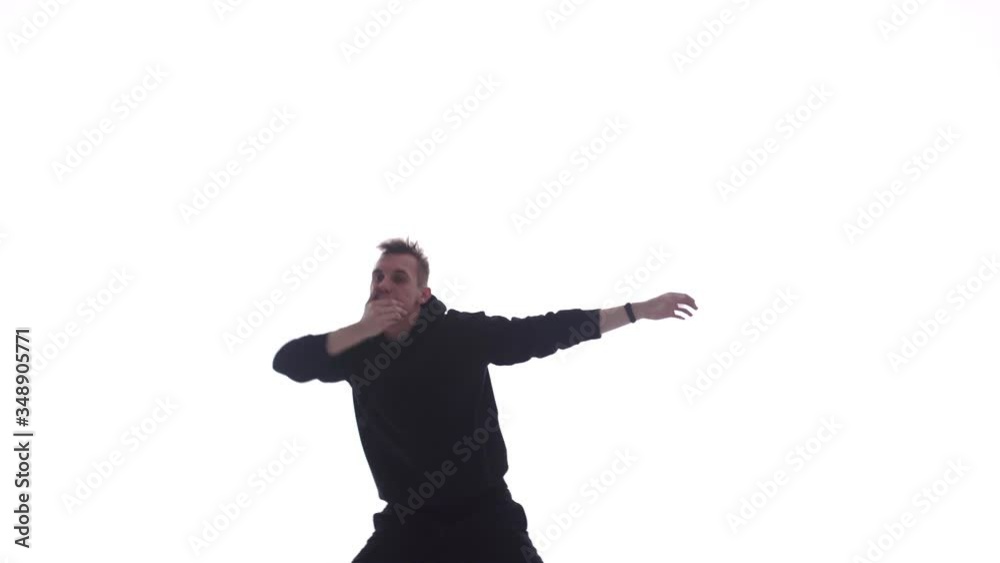Medium long shot of young handsome man in black tracksuit vigorously dancing hip hop, freestyle, street dance, isolated Medium long shot of young handsome man in black tracksuit vigorously dancing hip hop, freestyle, street dance, isolated