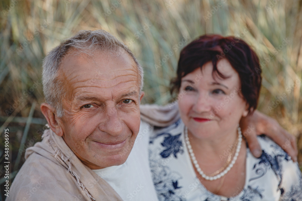 An old married couple on a summer walk in the field. In focus close up of the spouse's face