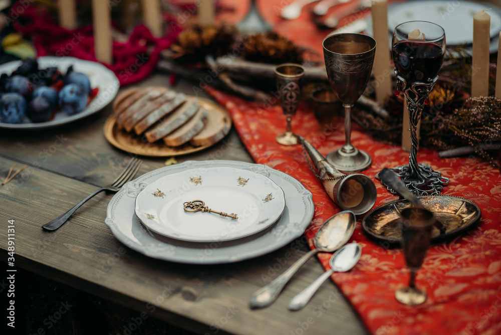 Antique dishes and iron wine glasses on the table with food Antique dishes and iron wine glasses on the table with food