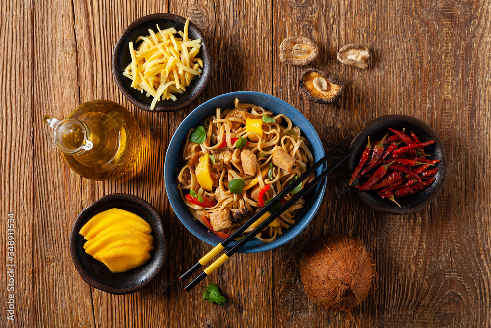Fried chicken with mango and coconut milk with noodles. Prepared in a wok. Top view. Served in a blue bowl. Fried chicken with mango and coconut milk with noodles. Prepared in a wok. Top view. Served in a blue bowl.