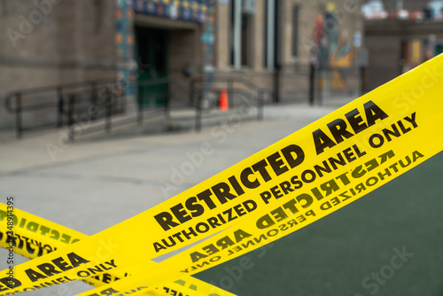 Close up view of an x shaped barrier of yellow restricted area caution tape blocking off a playground at a school in Chicago.