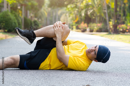 Runners catch the knee from accident on road in public park. Injury from run. Collapsed with pain, Sport and health care concept.
