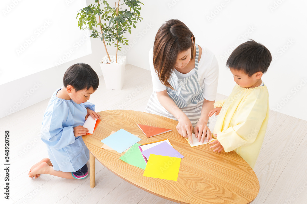 幼稚園で折り紙をする子どもと先生 幼稚園で折り紙をする子どもと先生