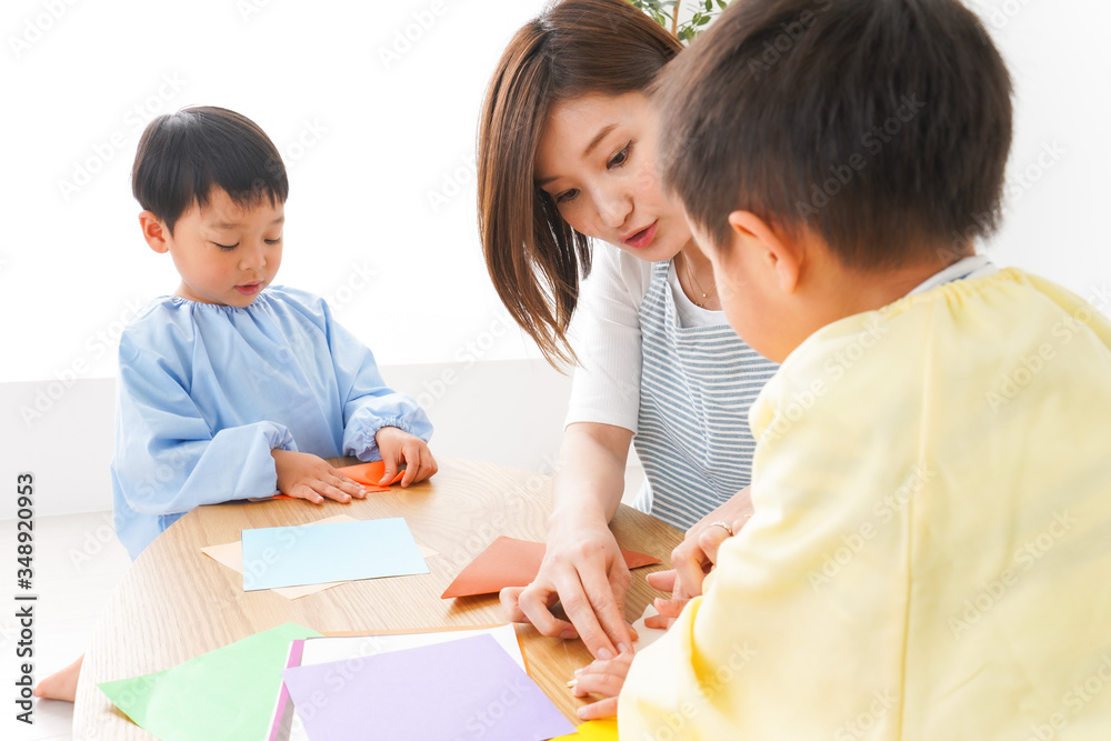幼稚園で折り紙をする子どもと先生