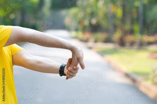 Sporty man stretching arm before workout. Fitness strong male athlete standing outdoor warming up.