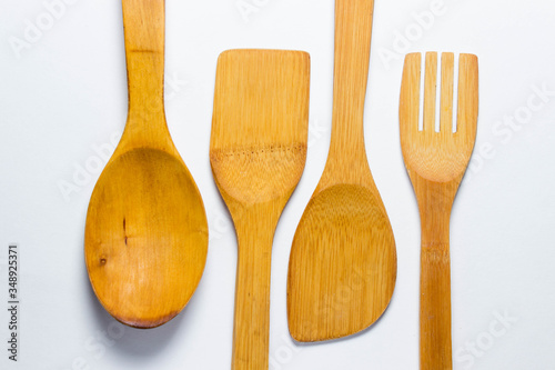 Four wooden cutlery lie on two different sides on a white background. Wooden spoon, wooden fork. And two wooden spatulas