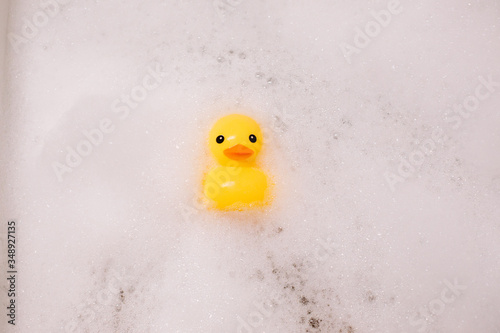 Yellow rubber duck in the bath with bubble foam