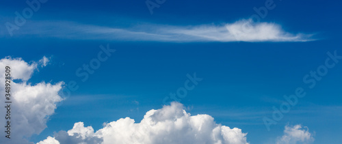 Wide background with copy space with white puffy clouds on a blue sky