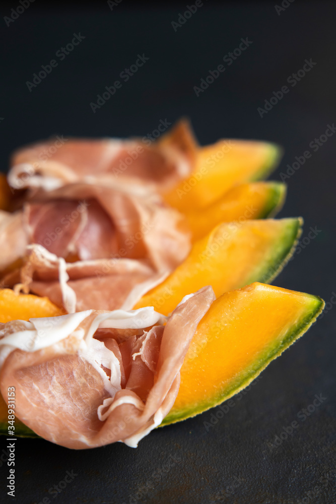 Food concept, prosciutto, ham with fresh melon on a dark background, top view with copy space, with space for your text, italiano snack, flat lay, honey melon or cantaloupe Food concept, prosciutto, ham with fresh melon on a dark background, top view with copy space, with space for your text, italiano snack, flat lay, honey melon or cantaloupe