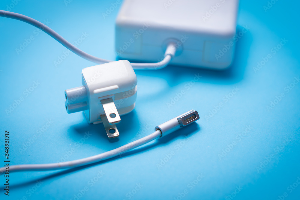 White laptop charger over blue background Technical assistance concept on computer peripherals. laptop chargers repair and maintenance concept. technology and computers topic White laptop charger over blue background Technical assistance concept on computer peripherals. laptop chargers repair and maintenance concept. technology and computers topic