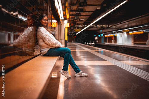 Beautiful young woman sited waiting for the train on a subway station