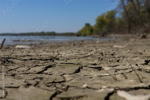 Cracked, muddy ground at the river bank with river Danube in background