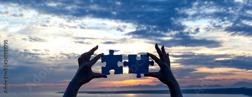 two hands connecting puzzle in sunset concept