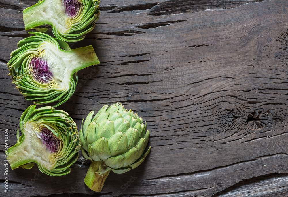 Obraz premium Green and purple artichoke flower edible buds on wooden background.