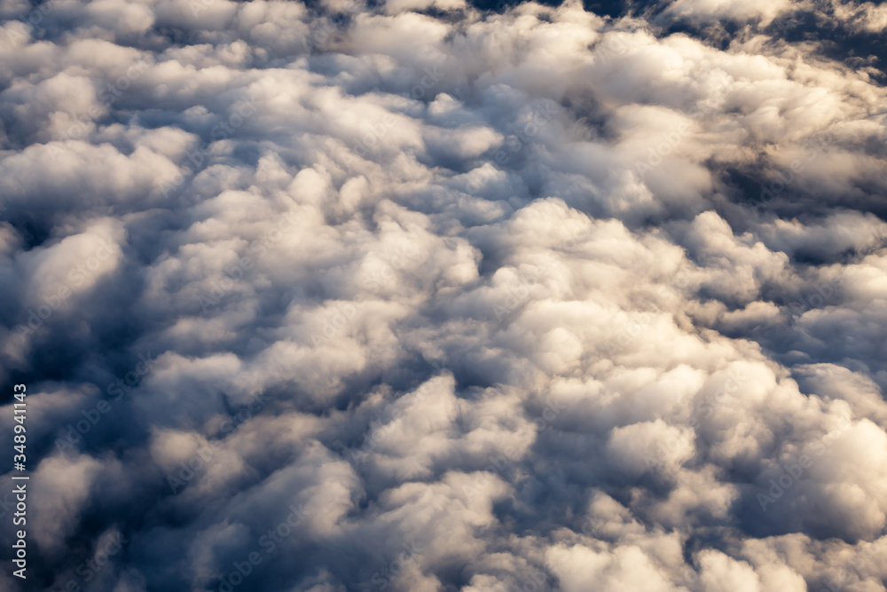 Aerial view from above a white and puffy clouds during a sunny sunrise. Taken from Airplane in British Columbia, Canada. Aerial view from above a white and puffy clouds during a sunny sunrise. Taken from Airplane in British Columbia, Canada.