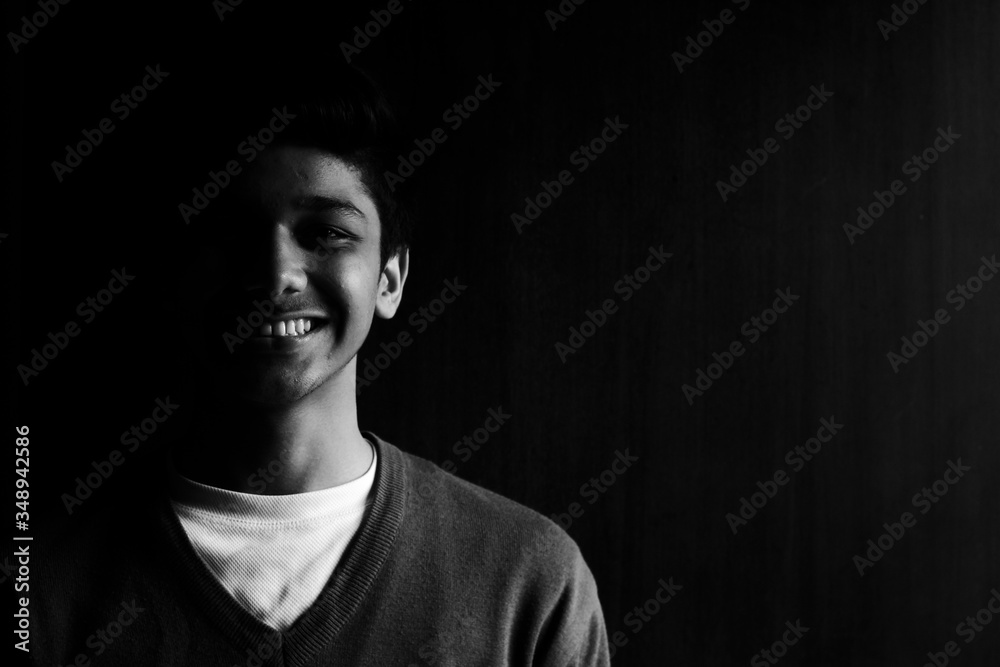 Low key portrait of a smiling young handsome boy in the dark 