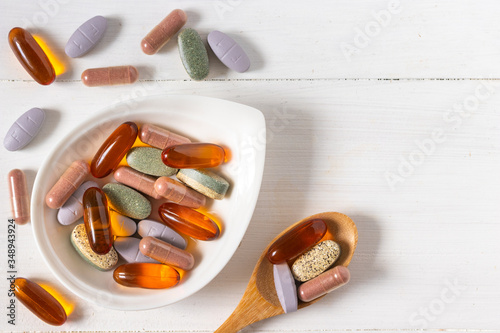 Variety of vitamin pills on white wooden background, supplemental and healthcare product, flat lay surface