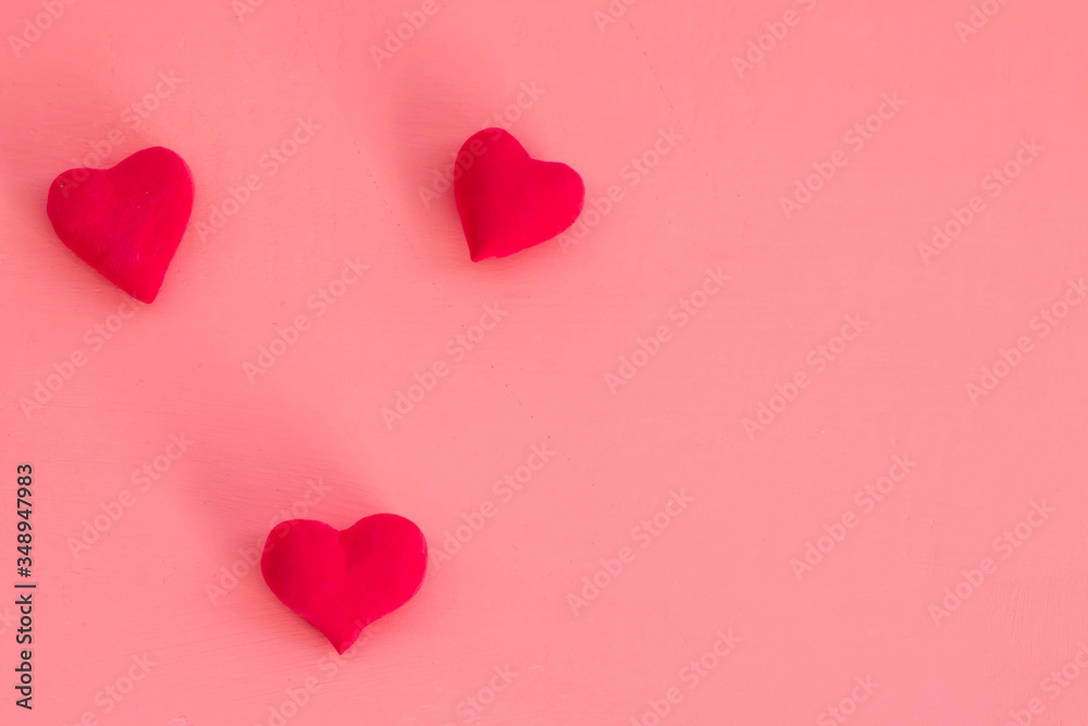 Red volumetric hearts on a pink background, place for text, copy space. Design on the theme of love. The photo