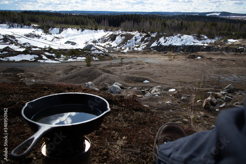 Cooking steaks and potatoes with cast iron frying pan next to sand pit at spring time.