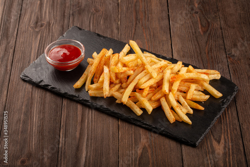 Fried fries on a stone black board, served with tomato ketchup.