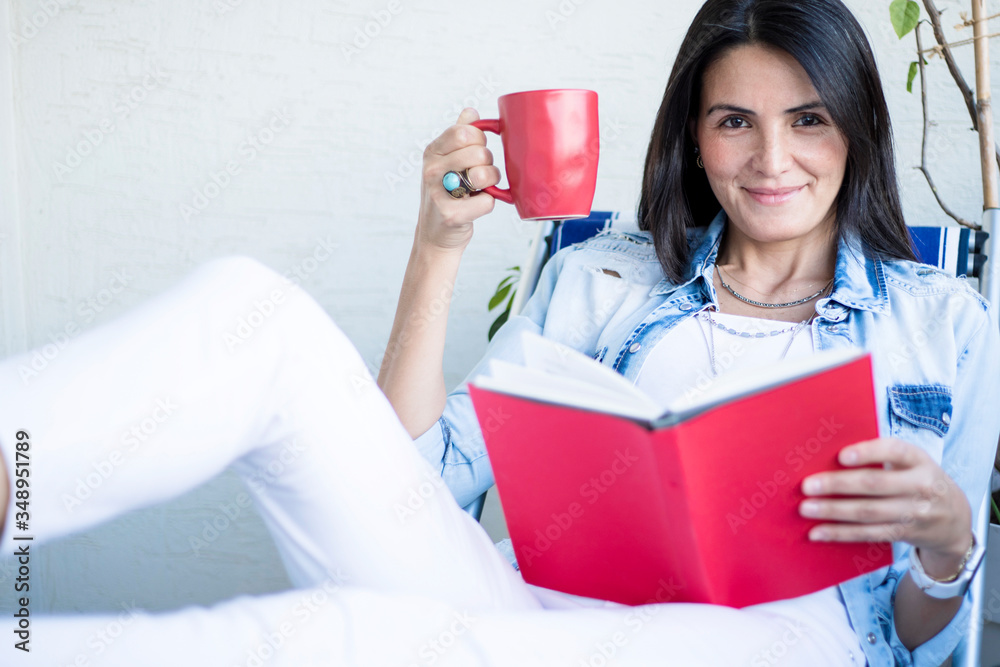 young woman relaxing with coffee and reading book