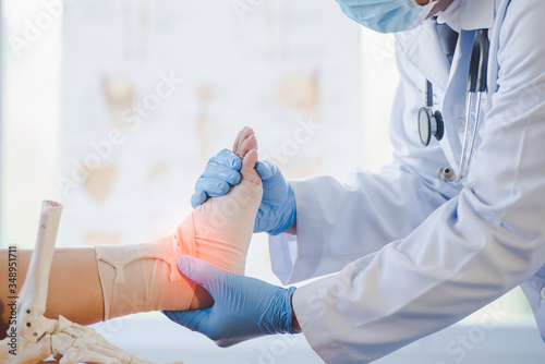Asian orthopedist or orthopedic doctor Wear a surgical mask and medical gloves. We are examining the cause of the ankle bone.