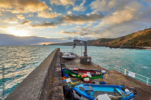 Image of the end of the harbour pier at Bouley bay with small fishing boats and headland at sunrise. Bouley Bay, Jersey Channel Islands. photo