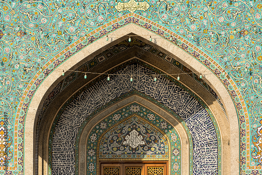 Exterior of mosque facade with white columns and amazing ornamental tiles decorating wall, Iran.