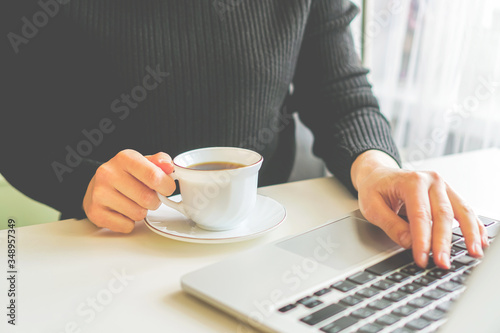 girl sits at a table, near a computer and a coffee mug