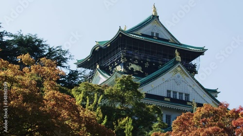 Osaka Castle in Japan on an autumn day with trees and light blue sky