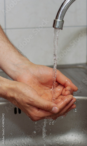 man washes his hands in the kitchen under the tap close up