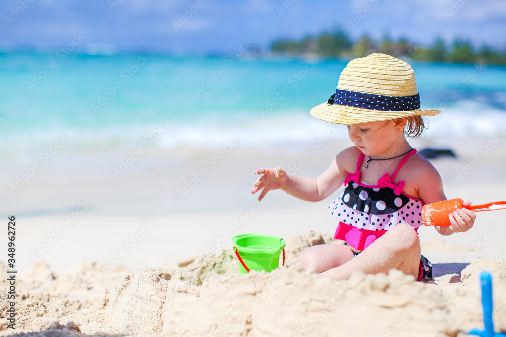 Little girl at tropical white beach making sand castle Little girl at tropical white beach making sand castle