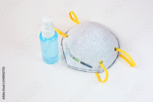 Medical filter face mask and alcohol gel laying on white background. Work from home concept. Stay at home during coronavirus cove 19. Hand made textile face mask on white background.