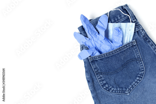 Classic blue jeans on the white background. Medical mask and gloves in the pocket. Pandemic concept. Copy space. Place for text and design. Top view. Flat layout