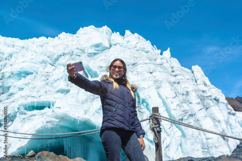 Beautiful girl in winter clothes takes a selfie at the Pastoruri Glacier, in the Huascarán National Park, Huaraz / Peru. Tropical glacier at 5200 meters above sea level. photo
